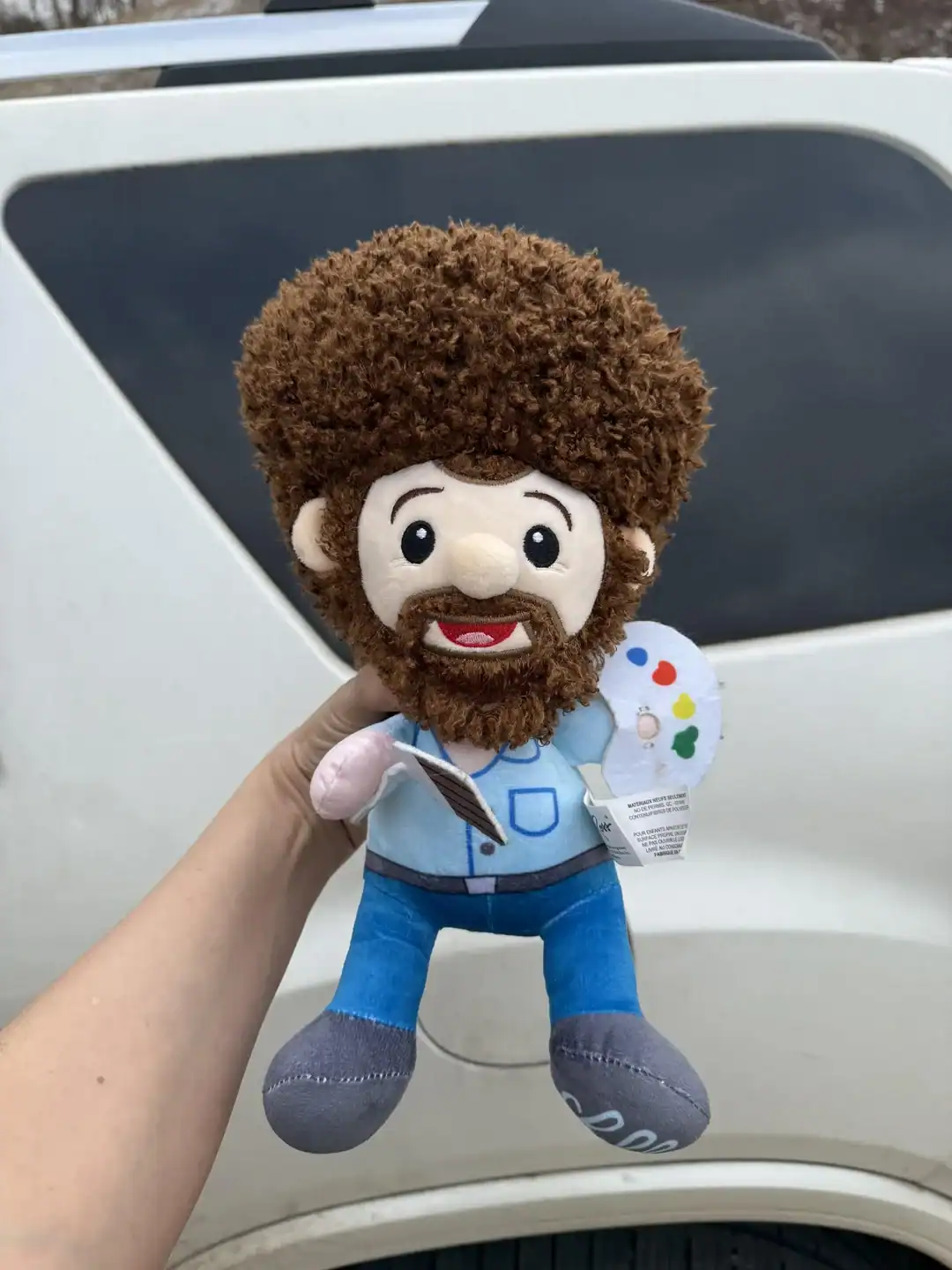 Cute plush doll of an artist with curly hair and beard, holding a paint palette and brush.