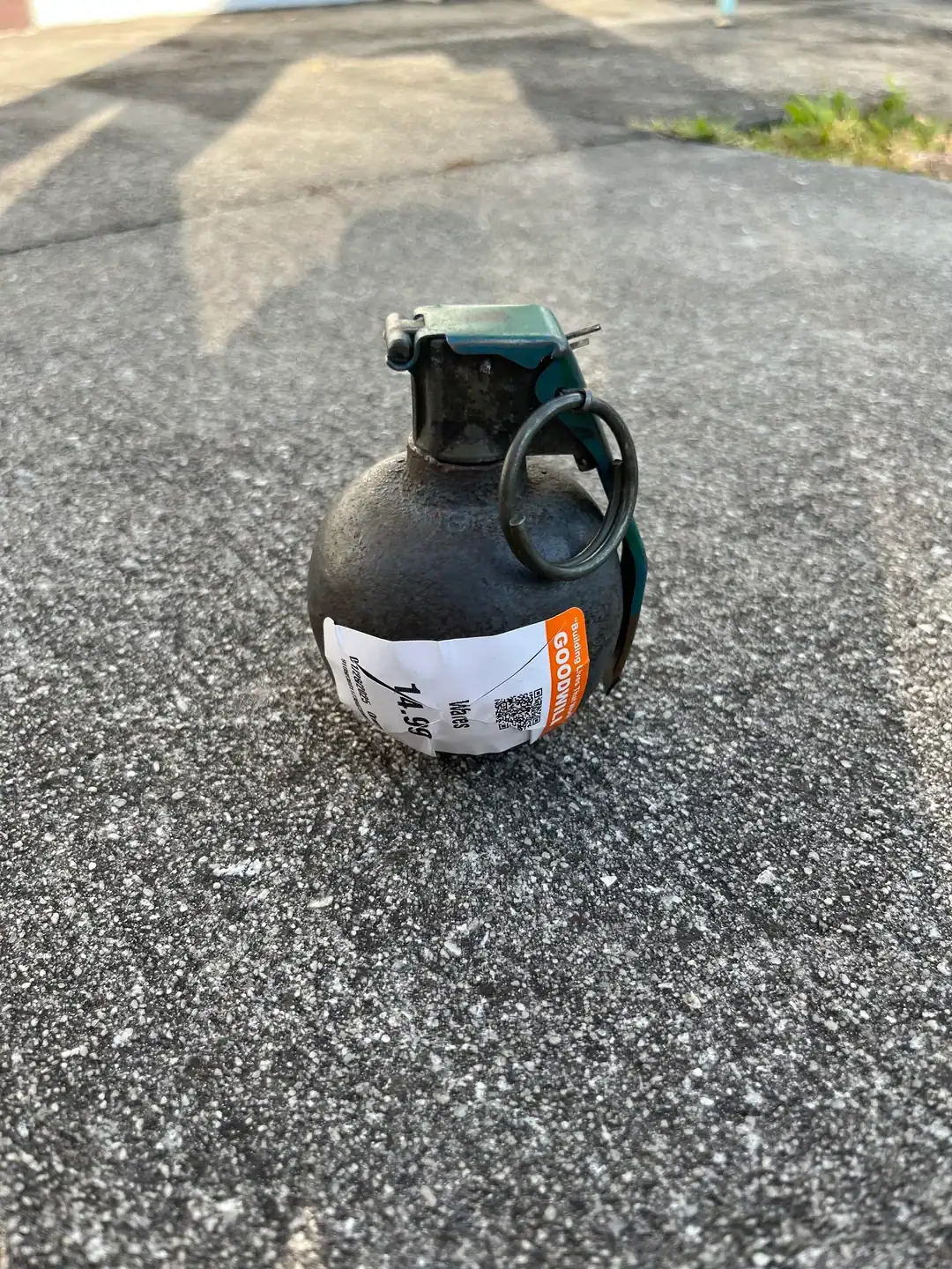 Toy hand grenade on asphalt surface, resembling a real grenade but is a plastic replica.
