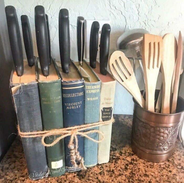 Vintage kitchen utensils and cookbooks on a countertop, featuring knives and spatulas in a decorativ.