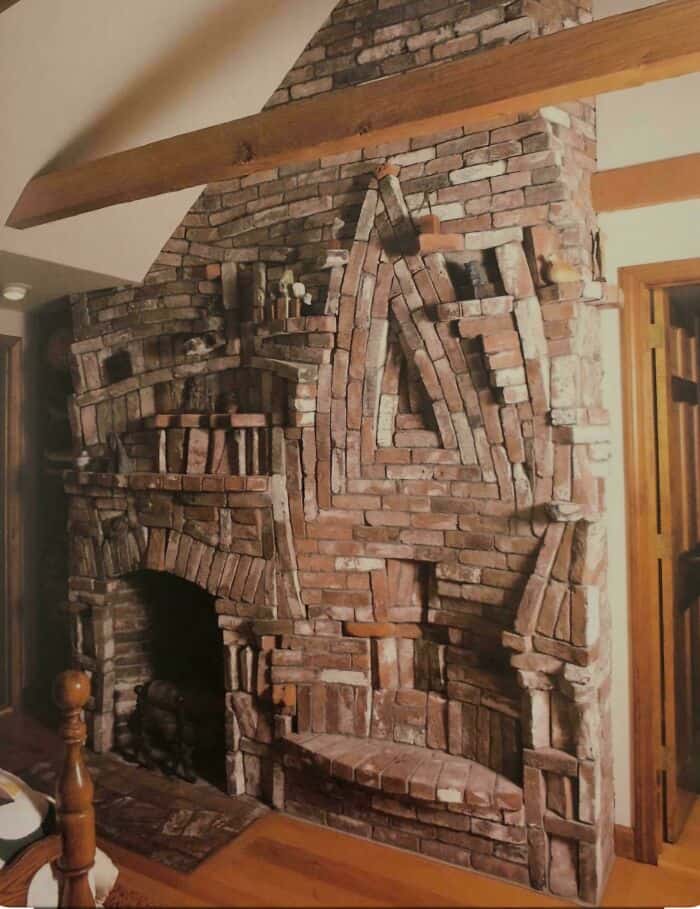 Fireplace with intricate brickwork and rustic wooden beams in a cozy living room setting.