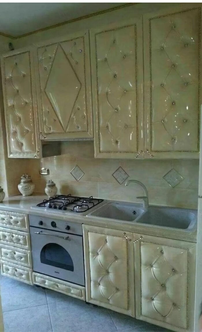 Tufted cream-colored kitchen cabinets with diamond patterns and decorative knobs, featuring a built-.