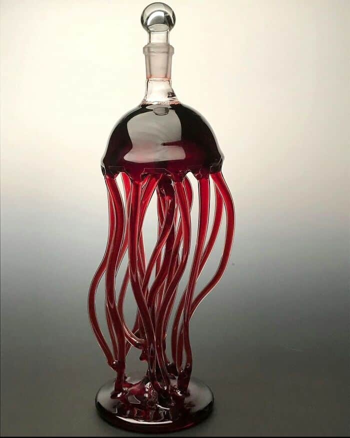 Jellyfish-shaped glass sculpture with red and clear tentacles, artistic and decorative piece.