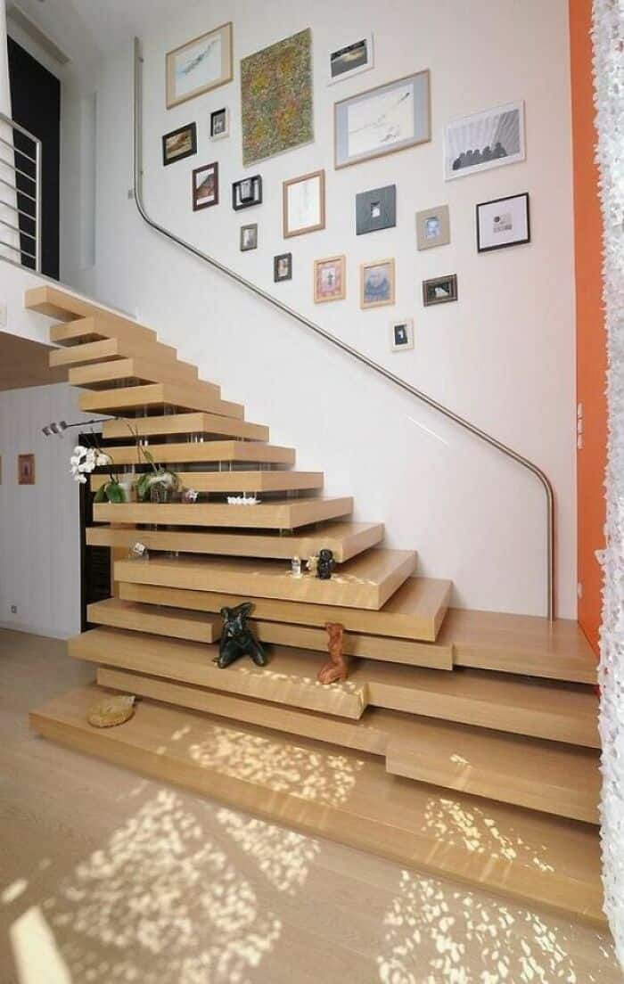 Stylish wooden staircase with floating steps and a gallery wall of framed artwork in a contemporary.