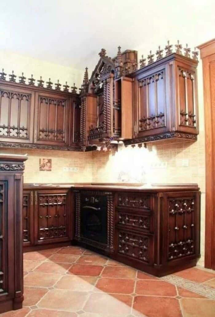 Gothic-style wooden kitchen cabinets with intricate carvings and a matching fireplace, showcasing an.
