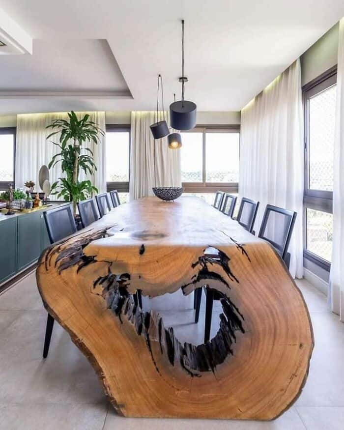 Spacious dining area featuring a unique live-edge wooden table, modern pendant lighting, and large w.
