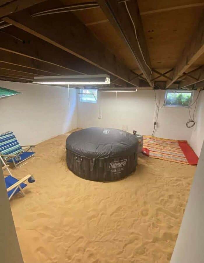 Indoor sand volleyball court with seating area, wooden ceiling, and small window for natural light.