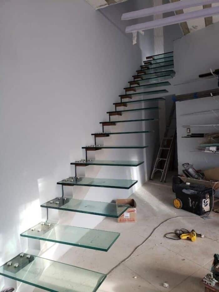 Glass staircase with metal supports in a modern home renovation project.