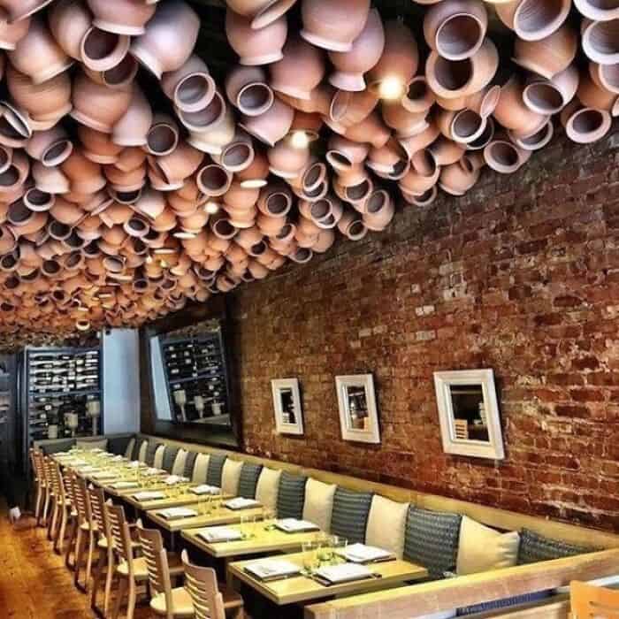 Ceiling decorated with hanging clay pots creating an artistic and rustic ambiance in a stylish resta.