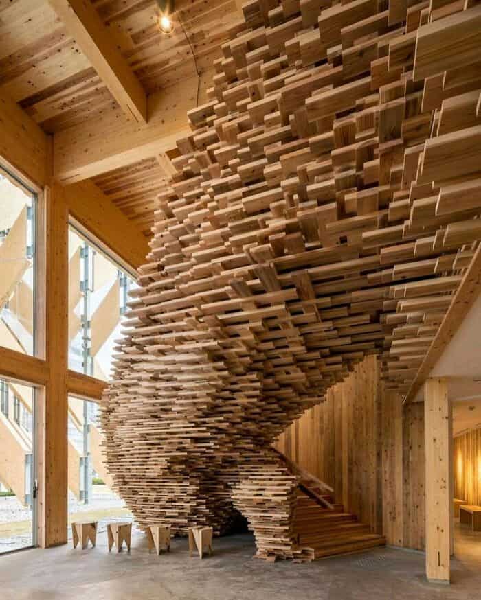Spiral staircase made of layered wooden planks in a modern interior.