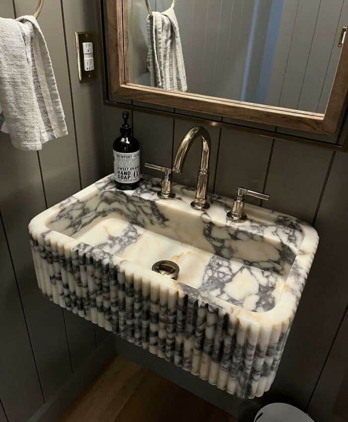 Vintage marble sink with brass faucet in a modern bathroom setting.