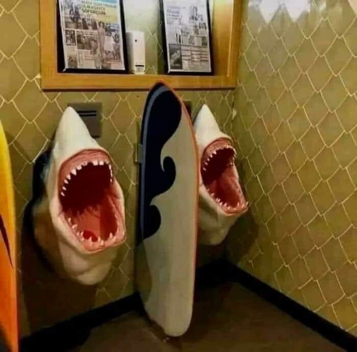 Shark-shaped surfboard with open mouth design on wall.