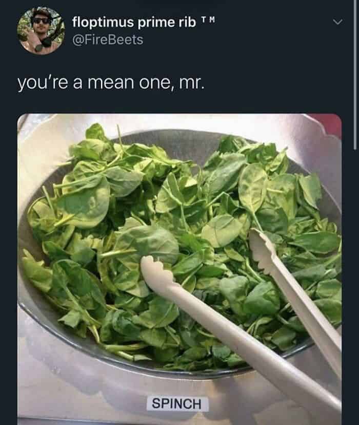 Healthy fresh spinach leaves in a stainless steel salad bowl with tongs.