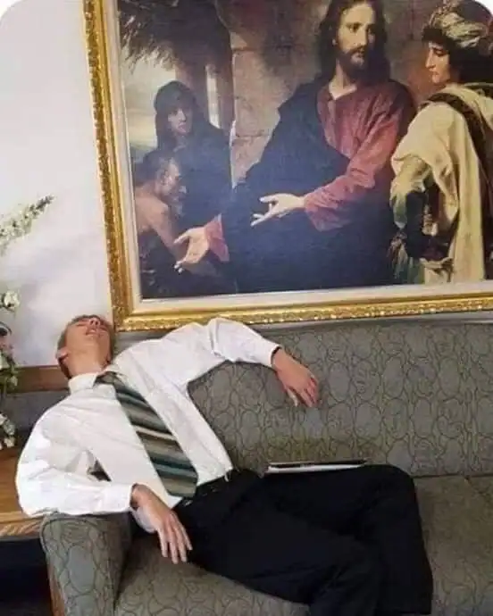 A man in a white shirt and striped tie sleeping on a sofa beneath a religious painting.