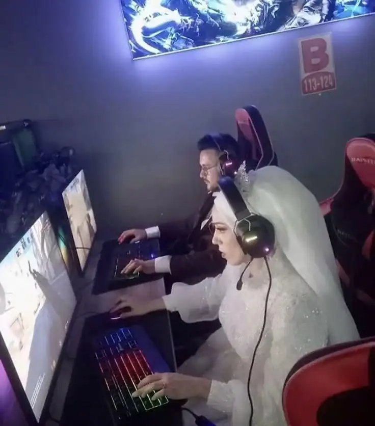 Bride and groom playing video games at an arcade.