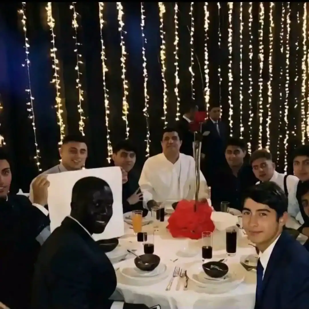 Celebrating at a festive dinner with string lights and a group of young men in formal attire.