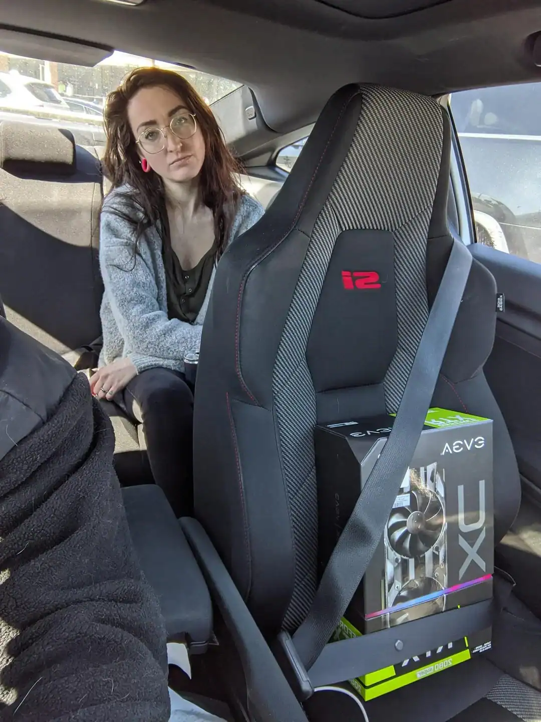 Woman sitting in the backseat of a car, looking at the camera.