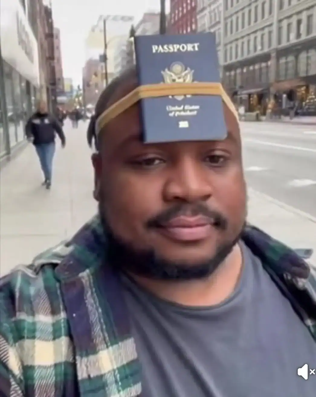 Passport on forehead with elastic band, man taking selfie on city street.
