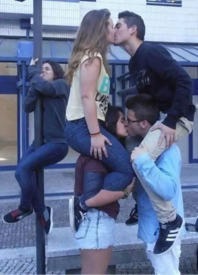 Kissing couple with friends in the background on a city street.