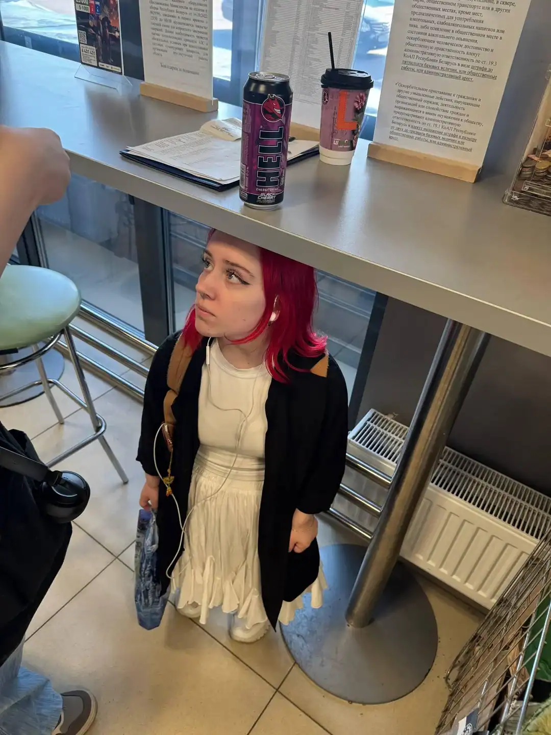 Young woman with red hair standing in a cafe, looking up.