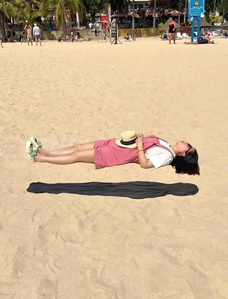 Woman lying on a towel on the beach, relaxing in the sun.