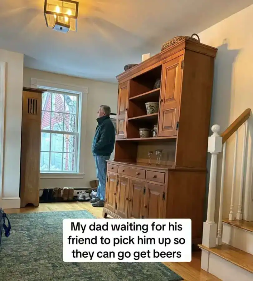 Dad waiting by window for friends to pick him up, humorous moment captured indoors.
