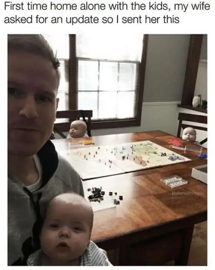 Man and baby at home with kids playing a board game on the table.