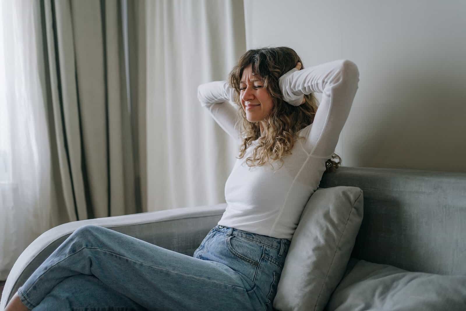 Woman relaxing on bed with hands behind head, smiling peacefully.