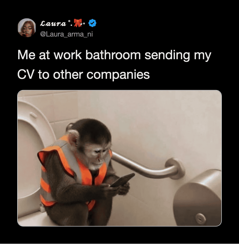 Monkey in a safety vest using a smartphone in a bathroom stall.