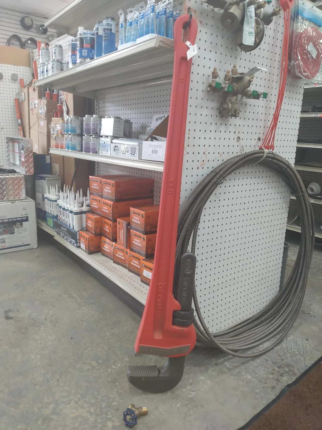 Red leaf blower with black cord leaning against a store shelf.
