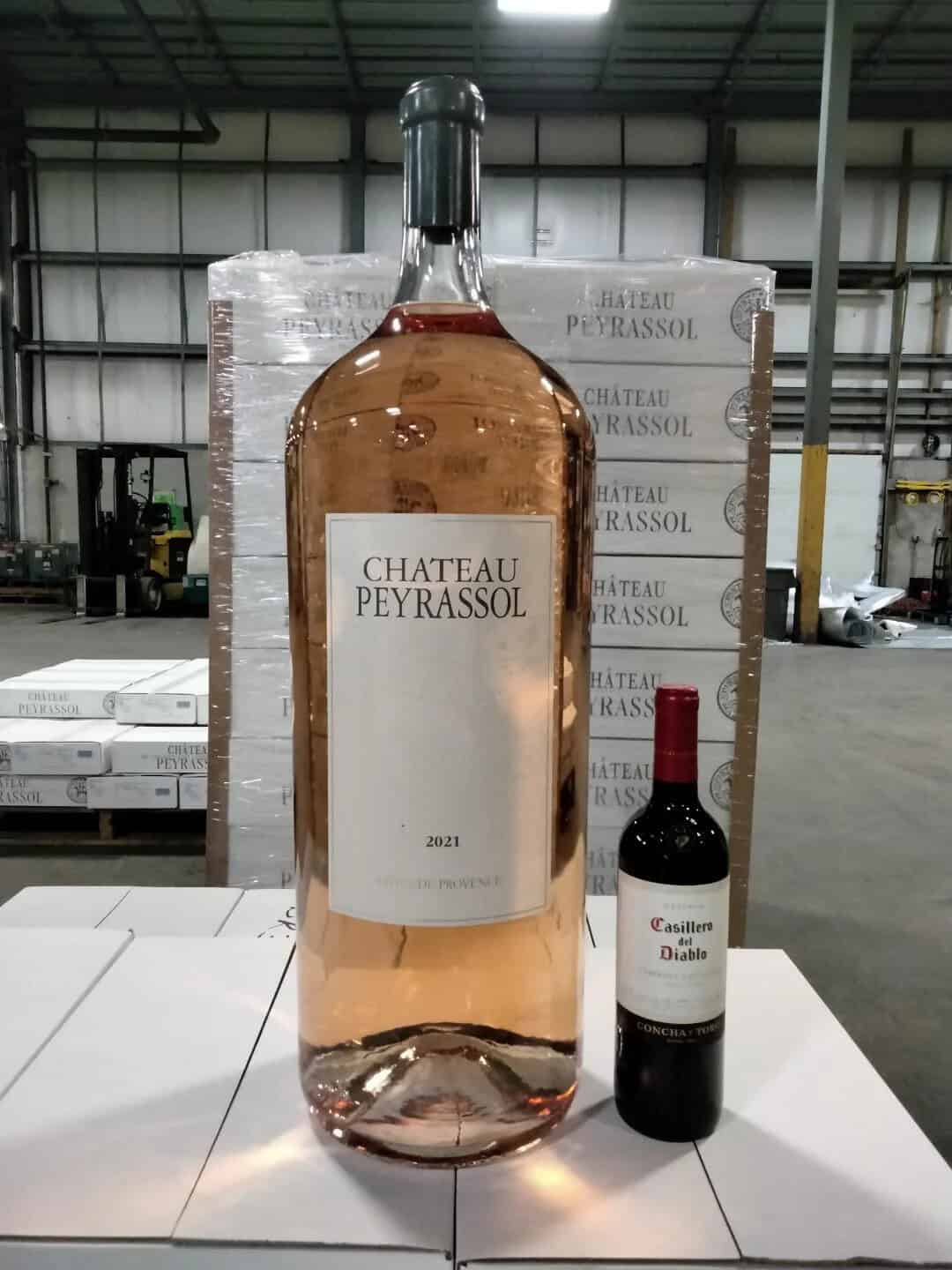 Large bottle of Château Peyrassol rosé wine next to a smaller bottle of Château Duhart wine.