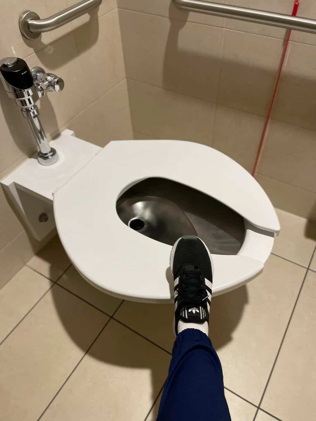 Toilet with a foot stepping on the seat in a public restroom.