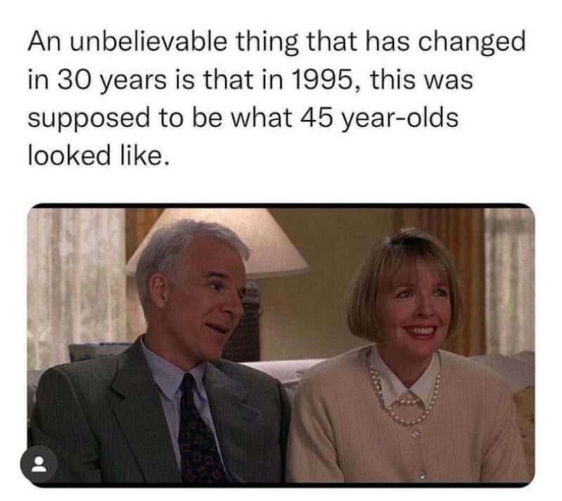Older man and woman smiling, sitting on a couch in a living room.