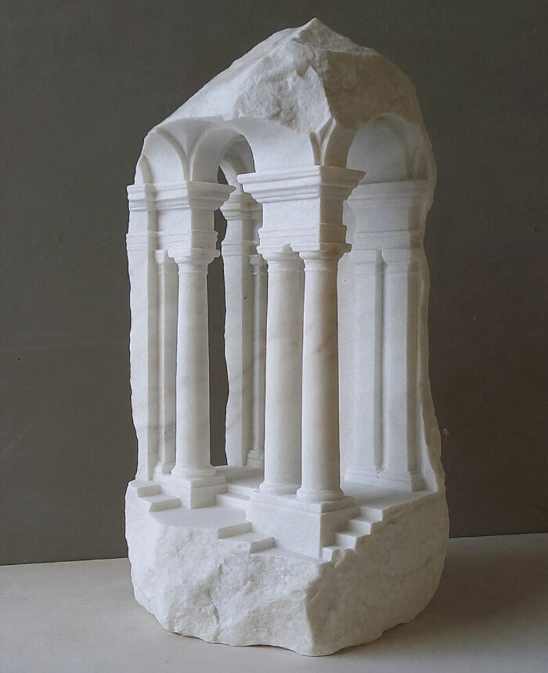 Marble sculpture of classical architecture with columns and arches on a stone base.