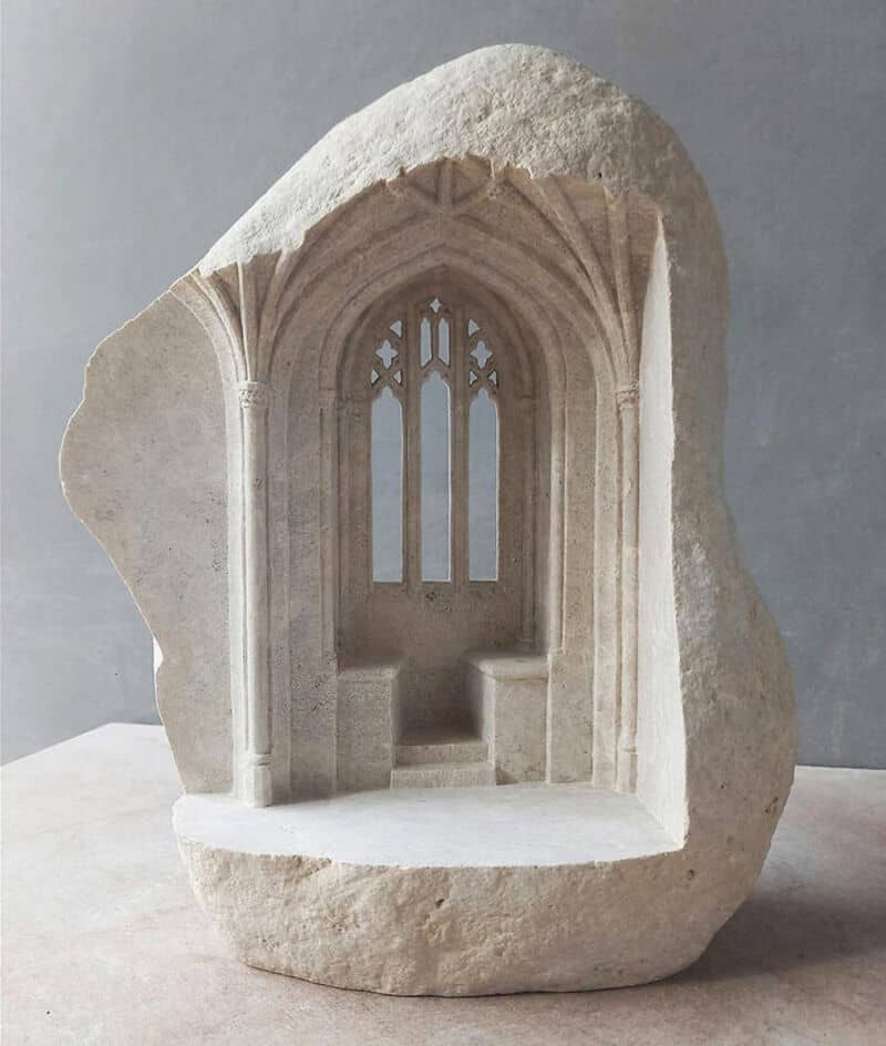 Marble sculpture of a Gothic-style window with intricate tracery and a small bench.