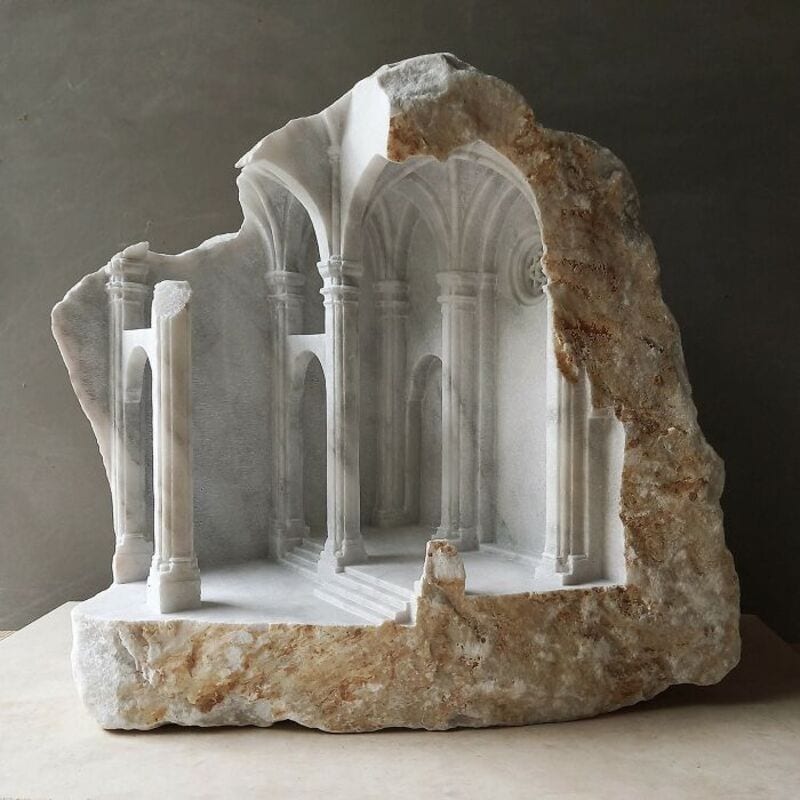 Marble sculpture of classical architecture with columns and arches, partially embedded in stone.