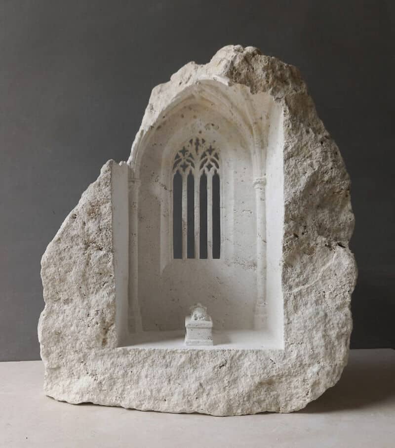 Marble sculpture of a Gothic window with a small altar below, carved into a rough stone block.