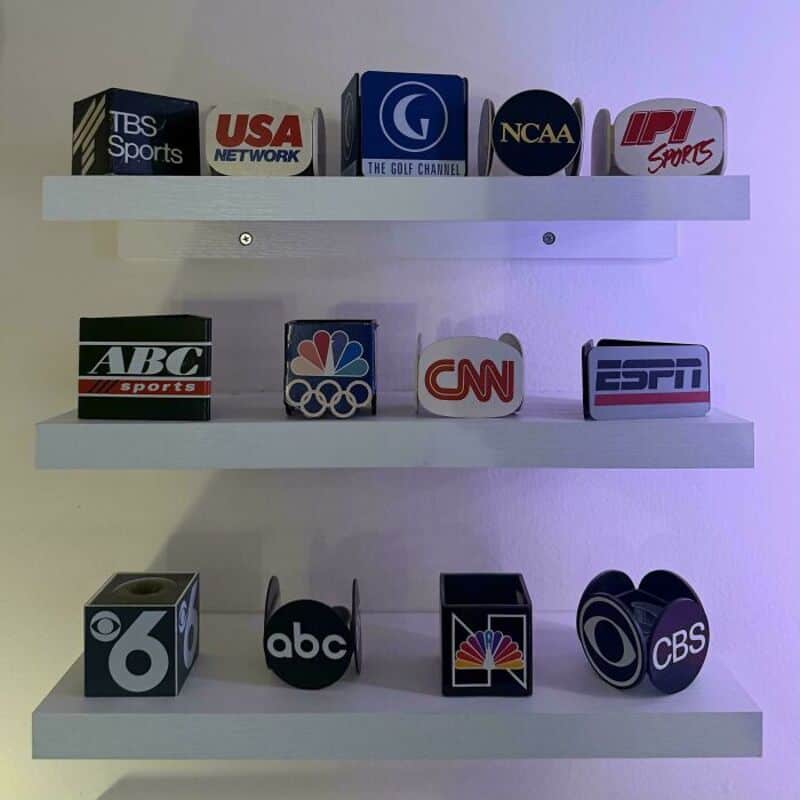 Collection of TV channel logos on white shelves, including ESPN, CNN, CBS, and others.