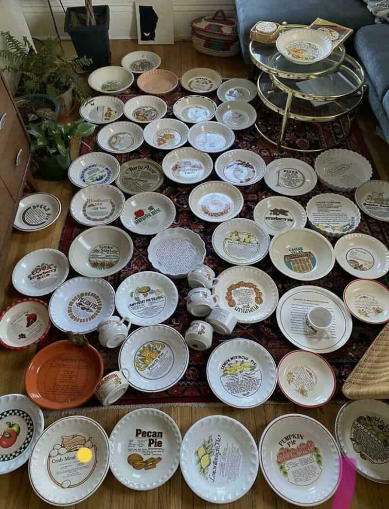 Collection of decorative and themed plates and mugs on a living room rug.