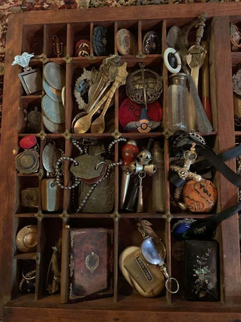 Collection of vintage and miscellaneous items in a wooden compartmentalized box.
