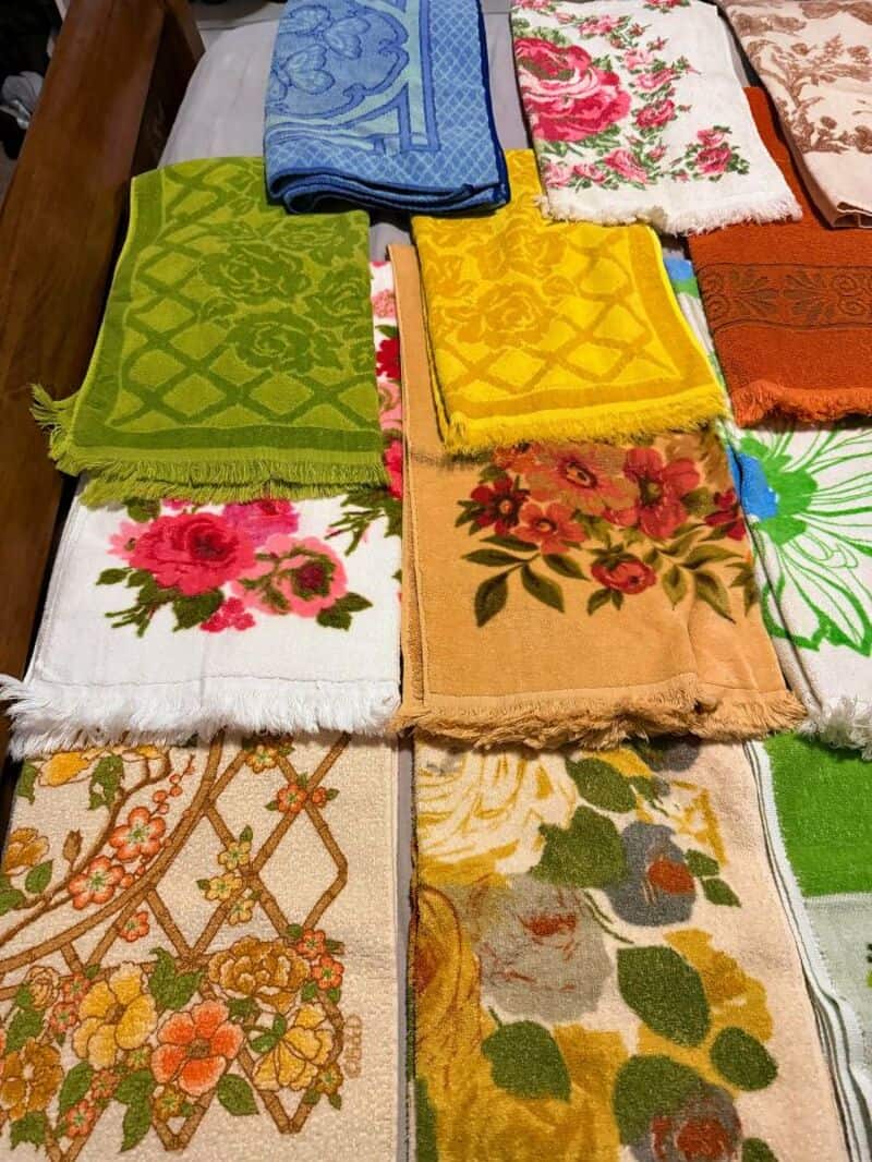 Colorful embroidered and patterned towels and cloths displayed on a table.