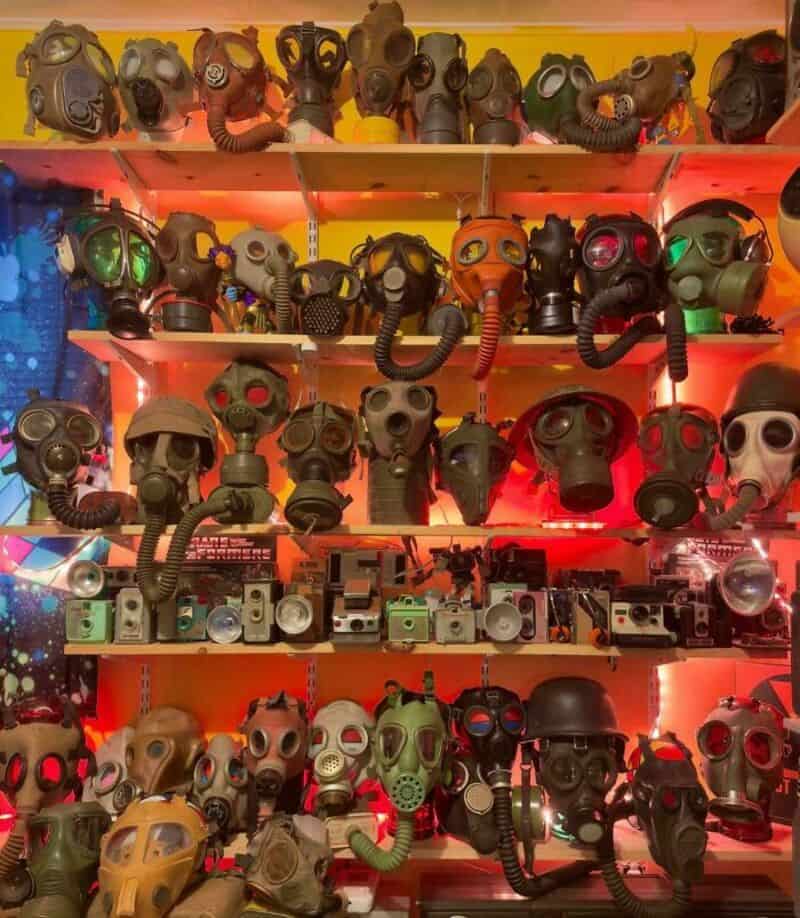 Collection of various gas masks displayed on shelves under red lighting.