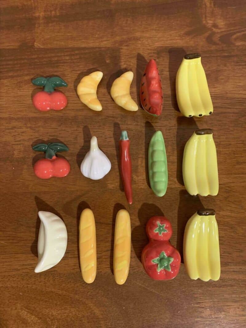 Collection of colorful plastic toy fruits and vegetables on a wooden surface.