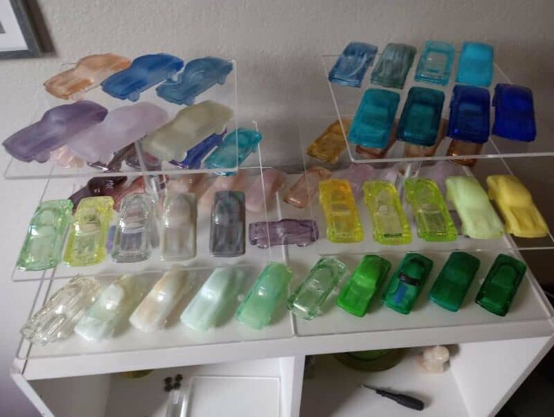 Colorful soap bars arranged on a white table, some on clear stands.