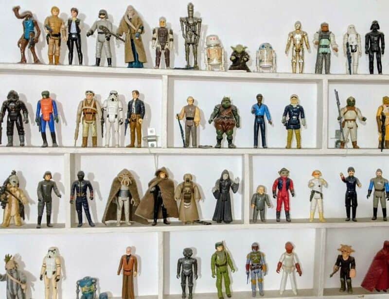 Collection of Star Wars action figures on white shelves.