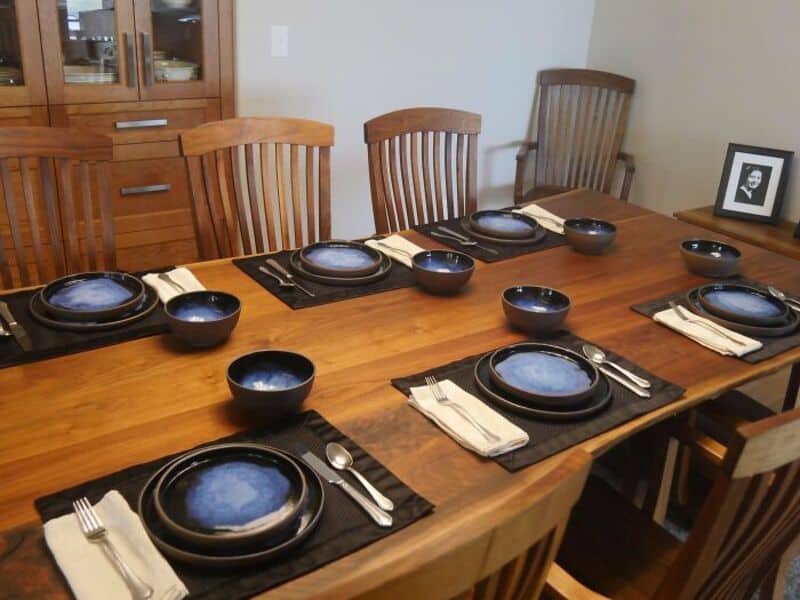 Dining table set with black plates, bowls, and silverware on black placemats.