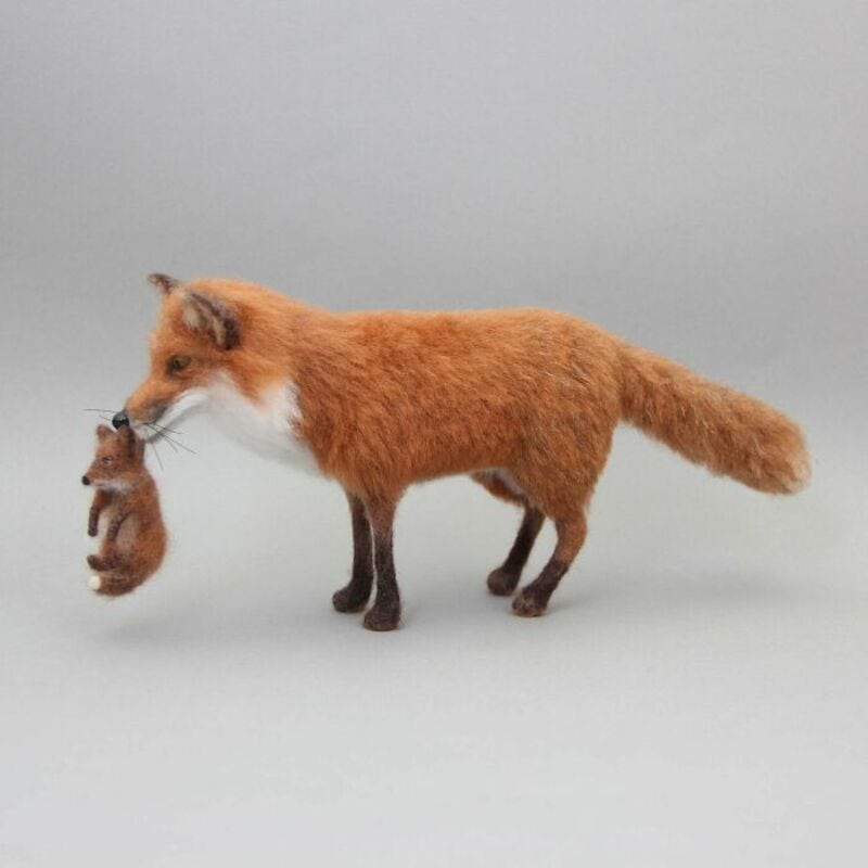 A1: Fox holding a tiny mouse in its mouth on a plain background.