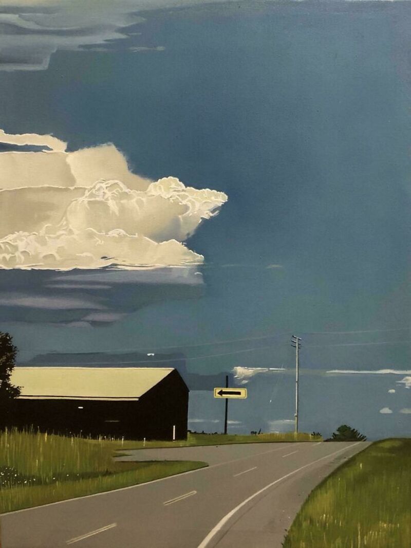 Rural road with a barn and dramatic cloud formation in the sky.