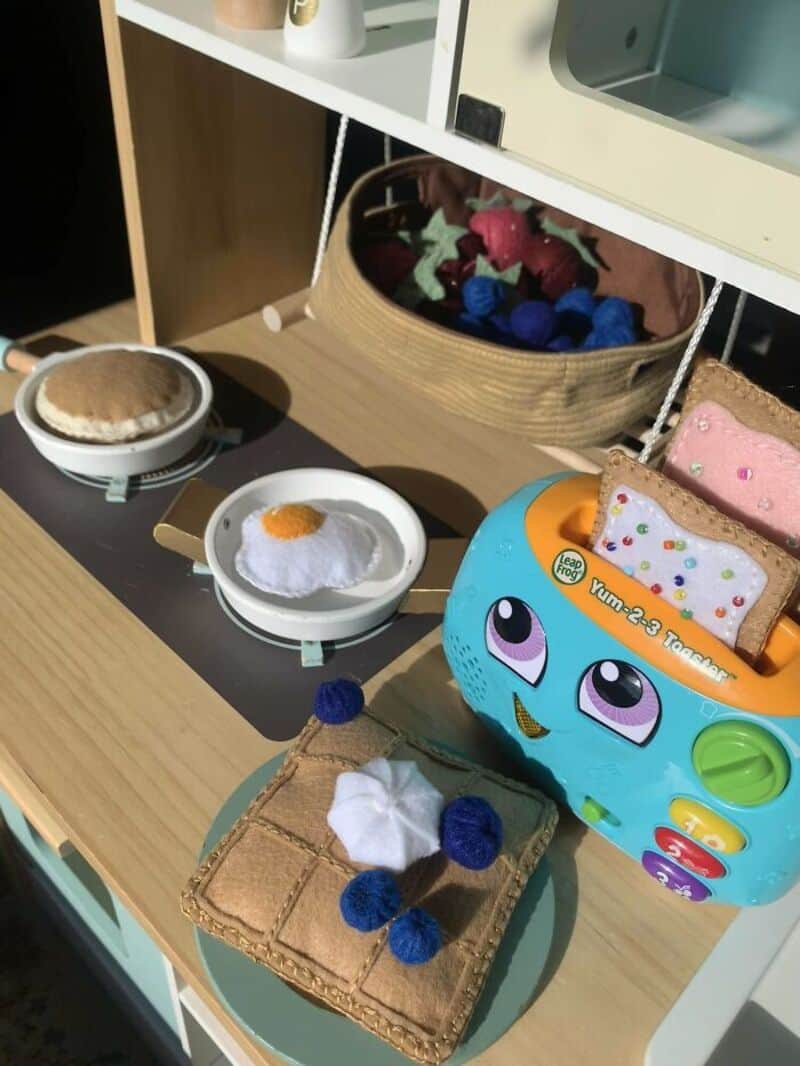 Toy bakery display with pretend food and colorful accessories.