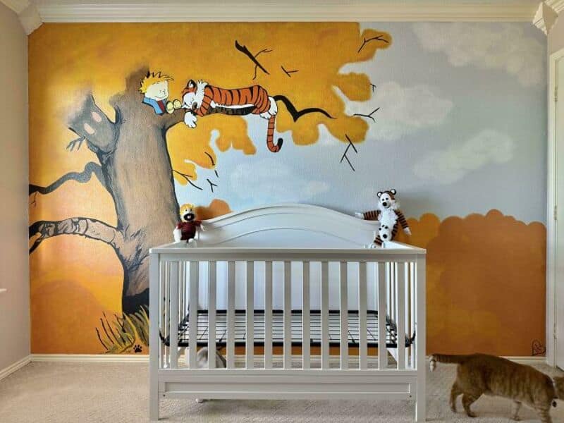 A colorful mural of Calvin and Hobbes on a tree with birds in the background, with plush toys on a w.
