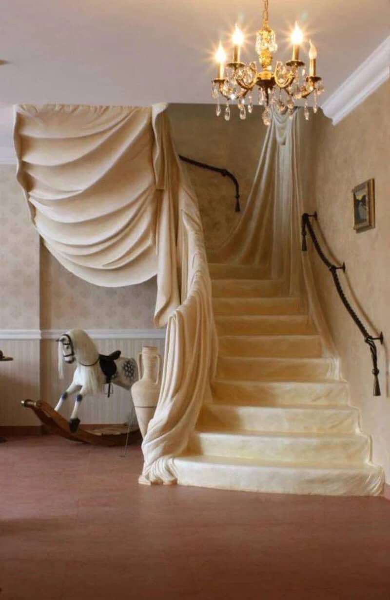 Elegant staircase with draped fabric and chandelier in a luxurious interior.